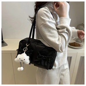 Vue détaillée du sac polochon noir en nylon avec poches à ruban et breloque nuage souriant