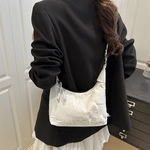 Elegant white floral lace bucket bag with shoulder strap shown on a model in a minimal room