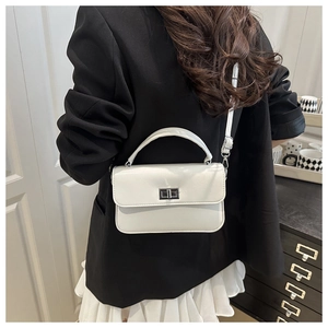 Detailed view of a white leather square handbag featuring a silver twist lock and slim strap