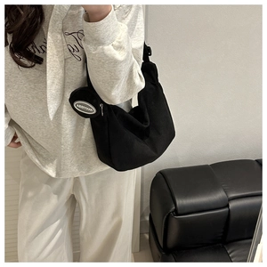 Détail d'un sac hobo en velours côtelé noir avec porte-monnaie porté par un modèle