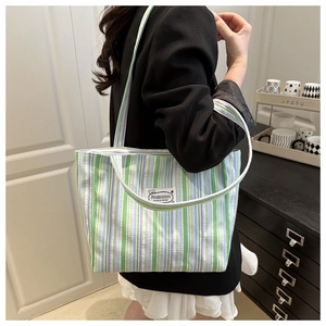 Detail of canvas tote bag featuring green and purple stripes with a fashion label tag