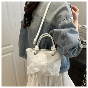 Detail of white lace bucket bag with 3D butterfly embroidery and adjustable strap