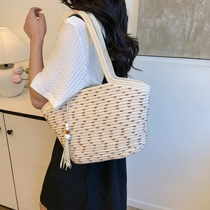 Large woven straw tote bag with brown polka dot pattern and tassel charm detail