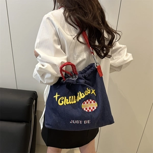 Blue denim bucket bag with red woven handles and Chill vibes embroidery for daily commute