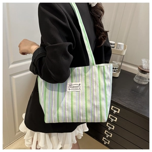 Detail of colorful striped canvas tote bag showing fashion tag and large capacity style