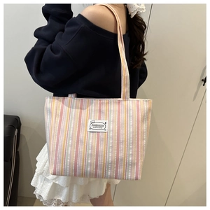 Detail of colorful striped canvas tote bag with fashion label worn on the shoulder