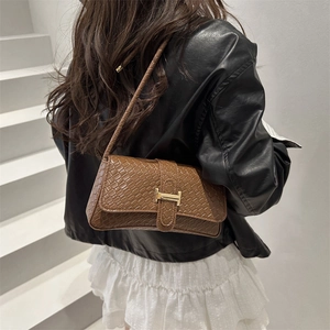 Bolso baguette de cuero marrón con hebilla en H usado por modelo en exterior