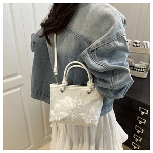 Detail of white lace bucket bag with 3D butterfly embroidery and leather strap