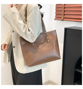 Close-up of minimalist brown tote bag featuring sleek leather texture and metal ring detail