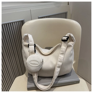 Détail du sac croissant en velours côtelé crème avec son petit porte-monnaie rond