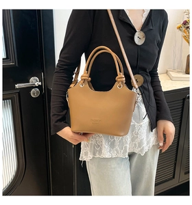 Detailed close-up of brown matte leather shoulder bag with FASHION M.G BAG text and silver hardware