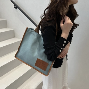 Light blue canvas tote bag with brown leather handles and large interior capacity