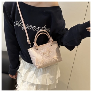 Detail of embroidered lace bucket bag with 3D butterfly appliques and crossbody strap