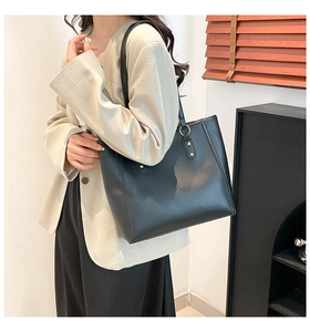 Close-up of black leather tote bag featuring gold ring details and elegant rivets