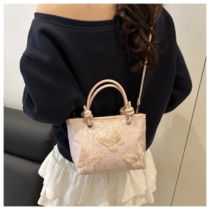 Detail of pink lace bucket bag with 3D butterfly embroidery and detachable strap