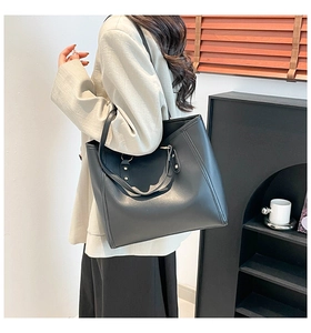 Detail of black matte leather tote bag with gold hardware and reinforced stitching