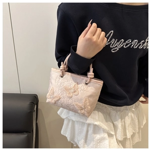 Close-up of pink bucket bag with delicate lace texture and 3D embroidered butterflies