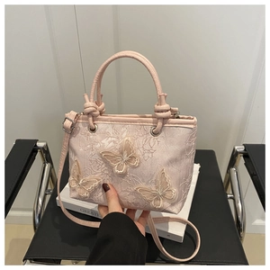 Detail of light pink bucket bag with 3D butterfly embroidery and floral lace texture