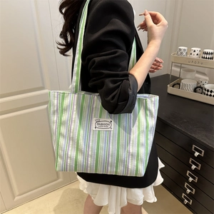 Chic green and purple striped canvas tote bag with fashion label on shoulder