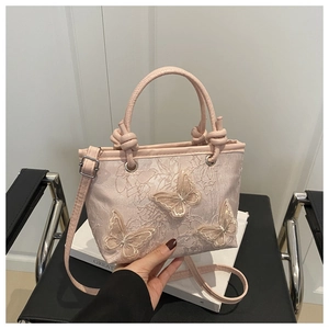 Detail of light pink bucket bag featuring lace embroidery and 3D butterfly appliqués
