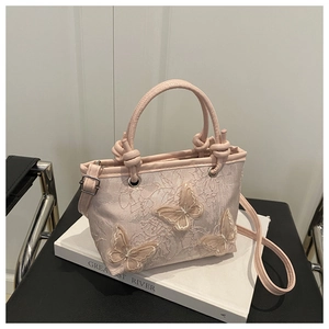 Detailed embroidery and 3D butterfly appliqués on pink bucket bag with knotted handle