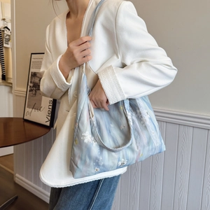 Borsa tote celeste con pizzo bianco e ricamo floreale indossata da una modella