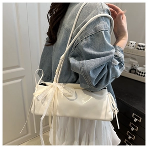 White baguette shoulder bag with lace trim and silk bow detail shown in lifestyle view