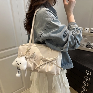 Sac oreiller beige avec nœud et breloque nuage porté par un mannequin à l'épaule