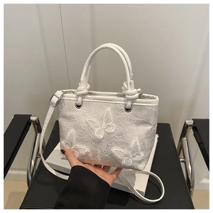 Detail view of white bucket bag with lace floral embroidery and 3D butterfly appliques