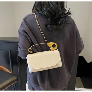 Off-white crossbody bag featuring a unique oversized gold paperclip handle and chain strap
