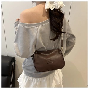Detail of dark brown pillow bag featuring FASHION label and jacquard woven strap