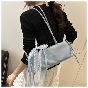 Detail of light blue patent leather baguette bag with lace bows and feminine accents