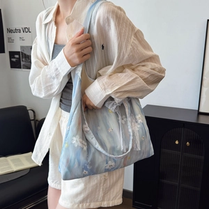 Borsa tote in tela azzurra con ricami floreali e pizzo in un ambiente minimalista