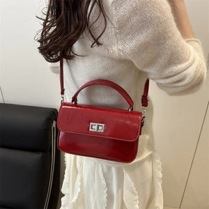 Glossy red square crossbody bag with silver buckle worn on a shoulder with white dress