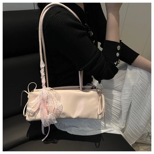 Detail of light pink baguette bag showing lace ribbon bow decoration on shoulder strap