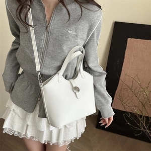 Stilvolle weiße Eimertasche aus Leder mit runder Metallschnalle an einem Frauenmodell