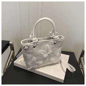 Detail of white floral lace tote bag featuring 3D butterfly appliqués and knotted handles