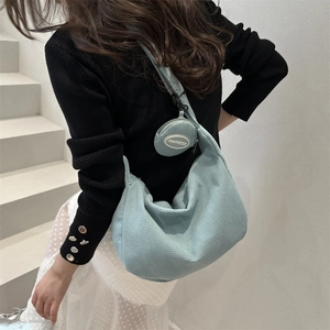 Sac fourre-tout bleu clair texturé avec petit porte-monnaie porté par un mannequin