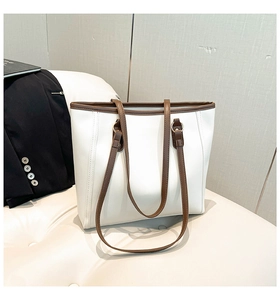 Close-up of minimalist white tote bag with brown leather handles on a white chair