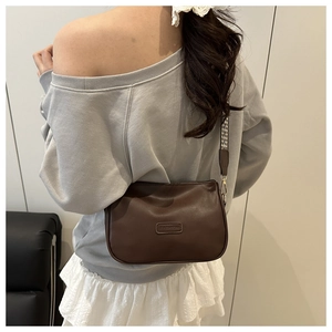 Detail of brown leather pillow bag with stylish geometric strap and FASHION logo