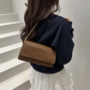 Dark brown faux crocodile baguette bag with shoulder strap shown on a model