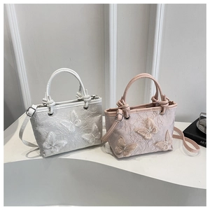Close-up detail of romantic bucket bag with lace texture and 3D butterfly embroidery