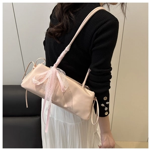 Close-up of light pink baguette bag featuring a large lace bow and drawstring detail