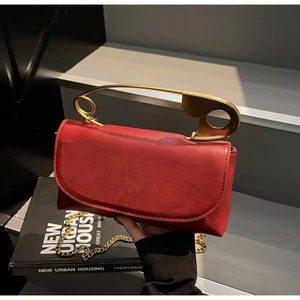 Detail of red square bag with matte faux leather and gold safety pin handle