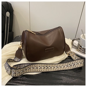 Detail of dark brown matte leather pillow bag with stylish zigzag pattern wide strap