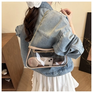 Detail of transparent PVC shoulder bag with beige leather trim and gold chain strap