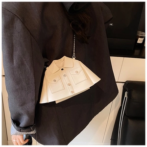 Close-up of a cream-colored jacket-shaped crossbody bag with a slim metal chain strap