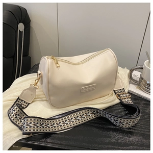 Close-up of stylish beige pillow bag featuring geometric pattern wide woven strap