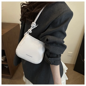 Detail of white bucket bag featuring a unique knotted shoulder strap and matte finish