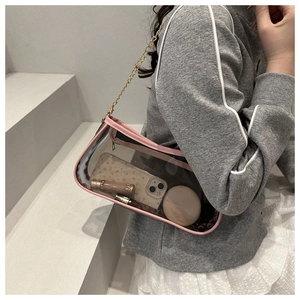 Detail of pink trim and golden chain on a transparent PVC underarm shoulder bag